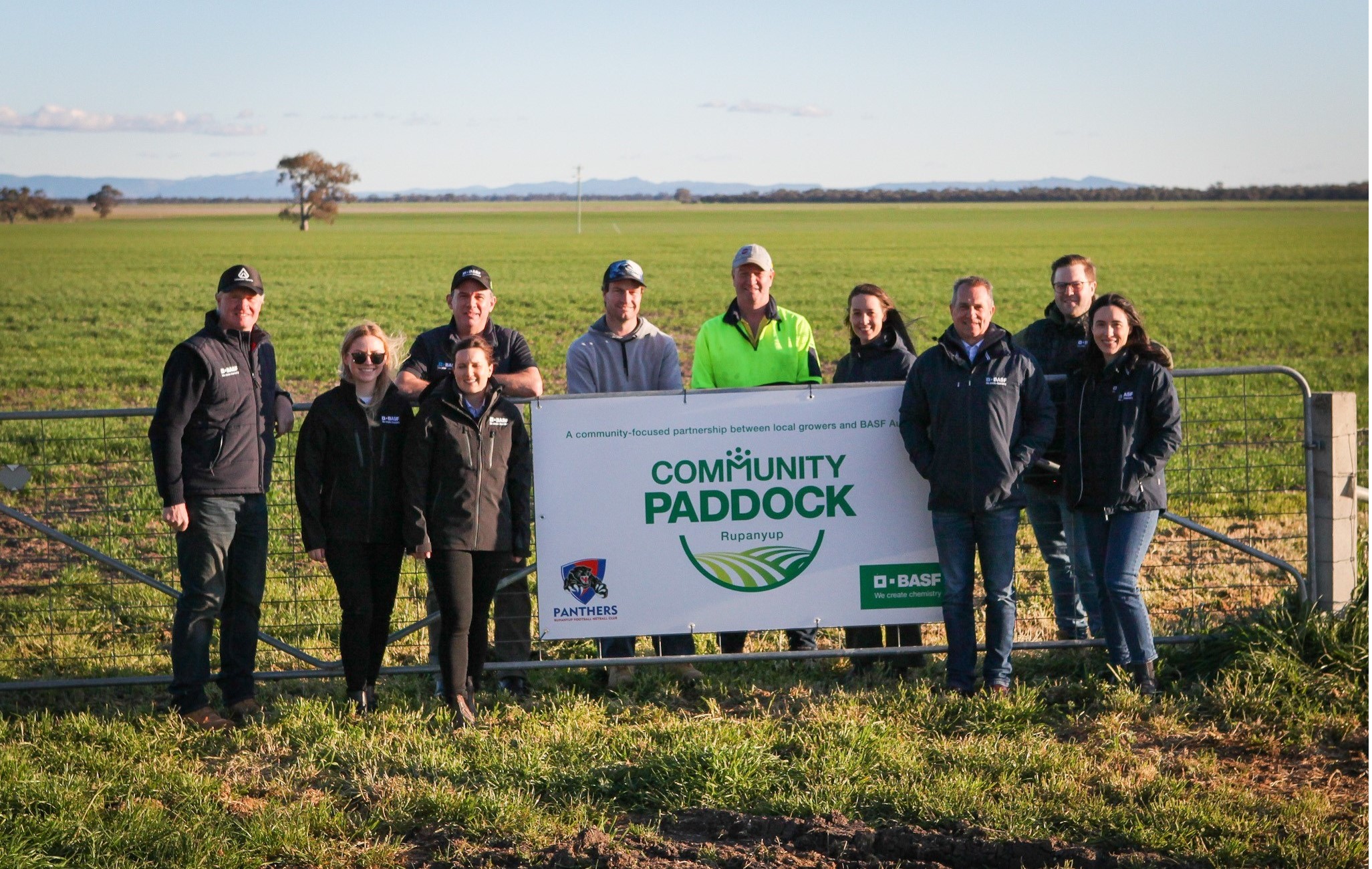 a group of people standing beside a sign that reads community paddock