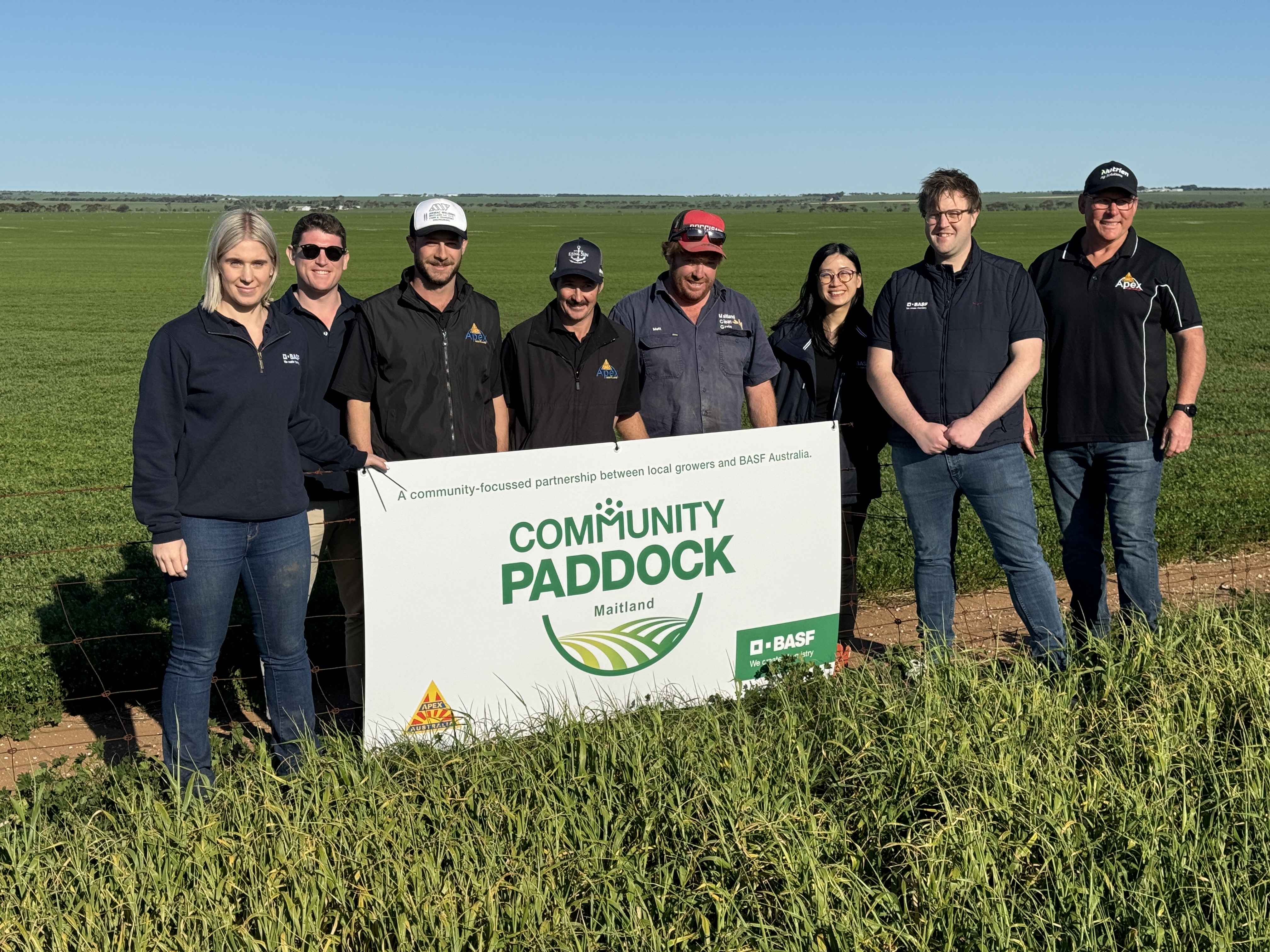 people standing beside a sign saying community paddock