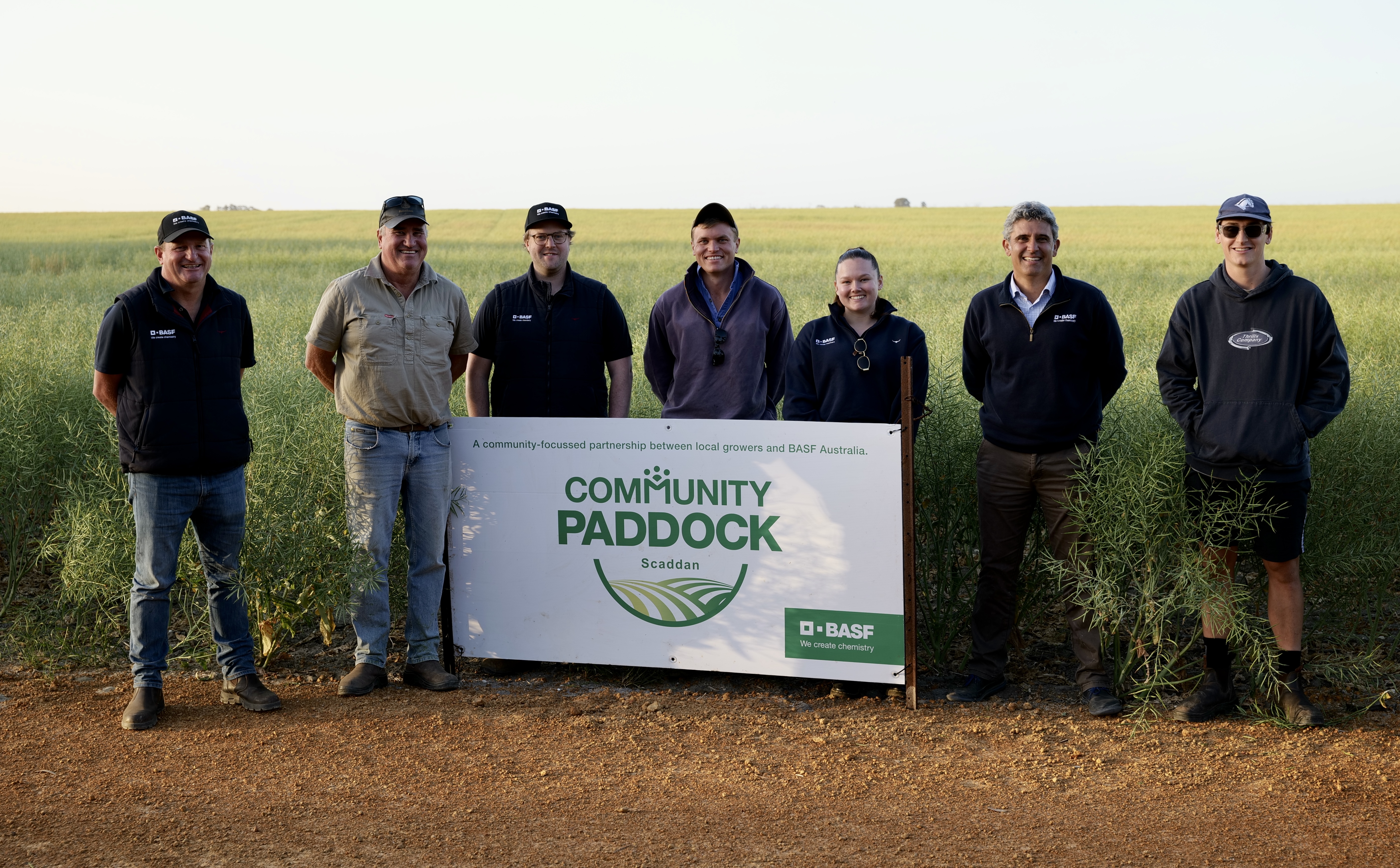 a group of people standing around a sign that says community paddock