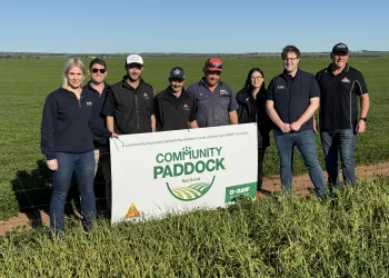 a group of people standing beside a sign saying Community Paddock