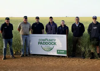 a group of people standing around a sign that says community paddock